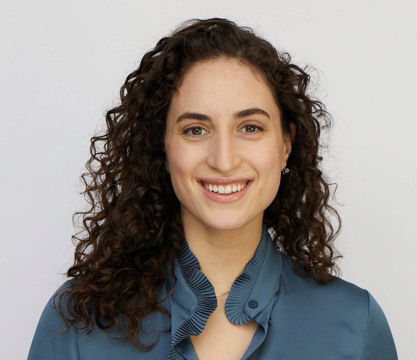 Smiling woman with curly hair in teal blouse
