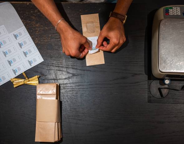 Hands labeling brown paper packages on table